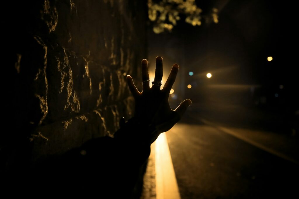 A hand being held out palm up toward a light at the end of a tunnel.
