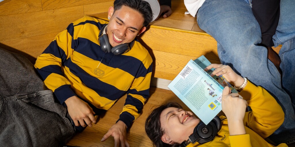 Two students laughing while one reads a book