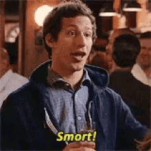 A man in a bar holds a drink and smiles, with the word Smort! in yellow text at the bottom of the image.