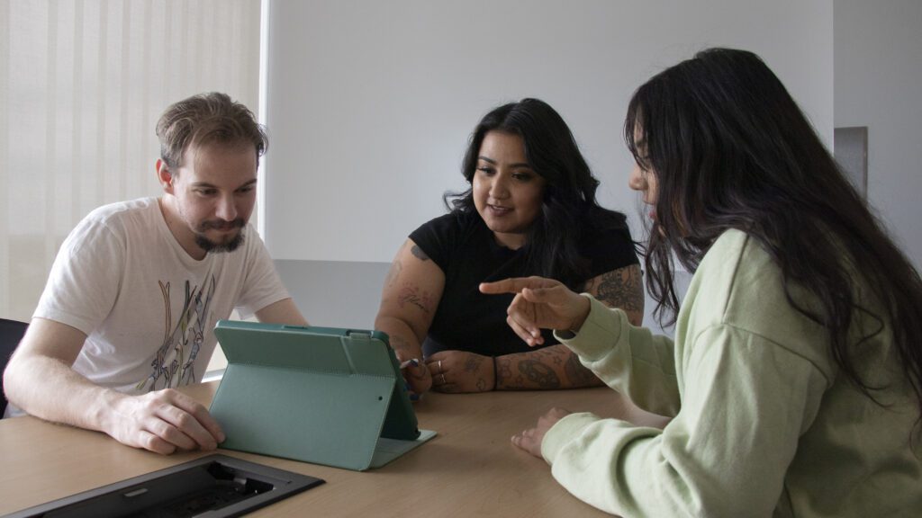 Picture of IGNITE student advocate Jessica Carrera helping two students.