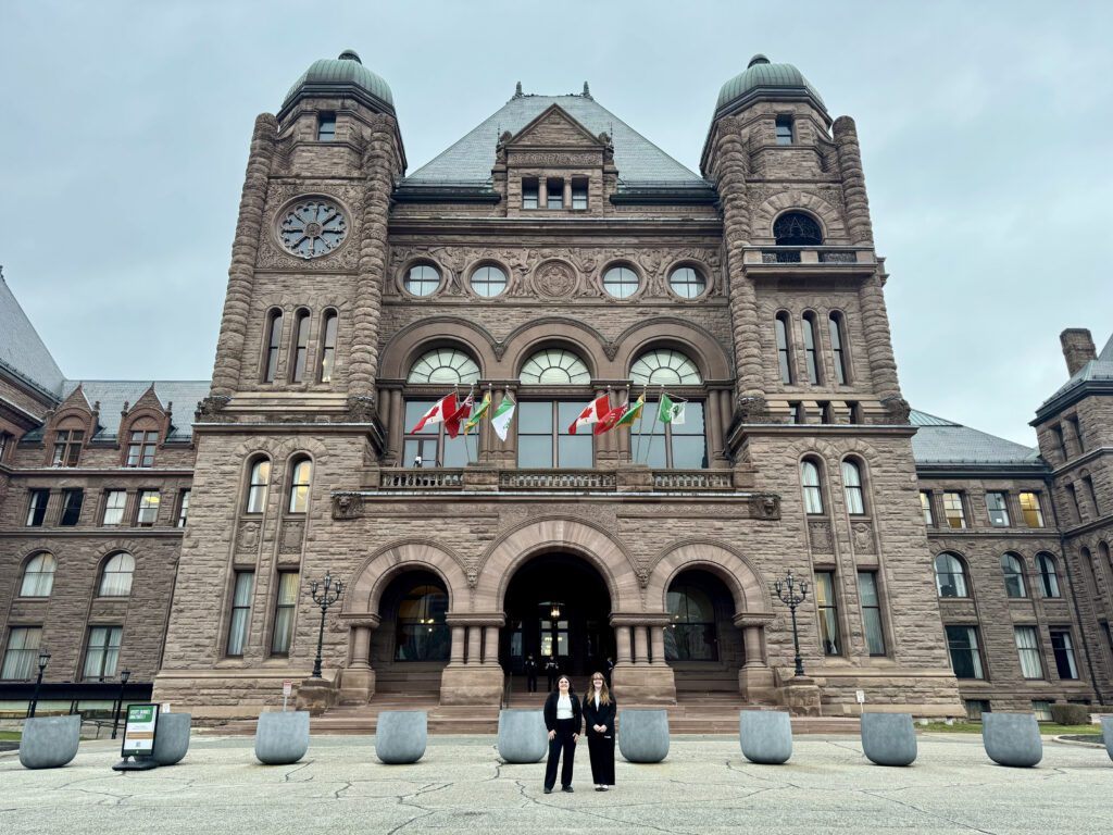Two people stand in front of Queen’s Park.