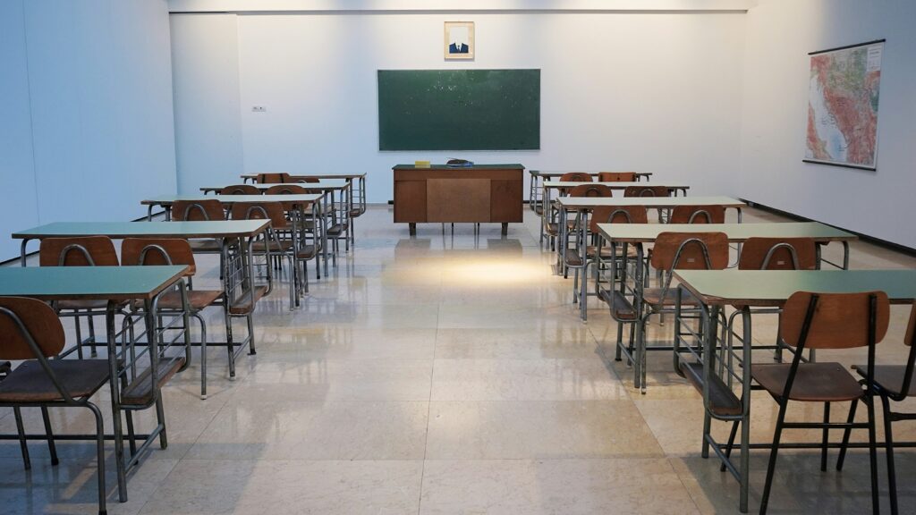 An empty classroom with desks and and a blackboard