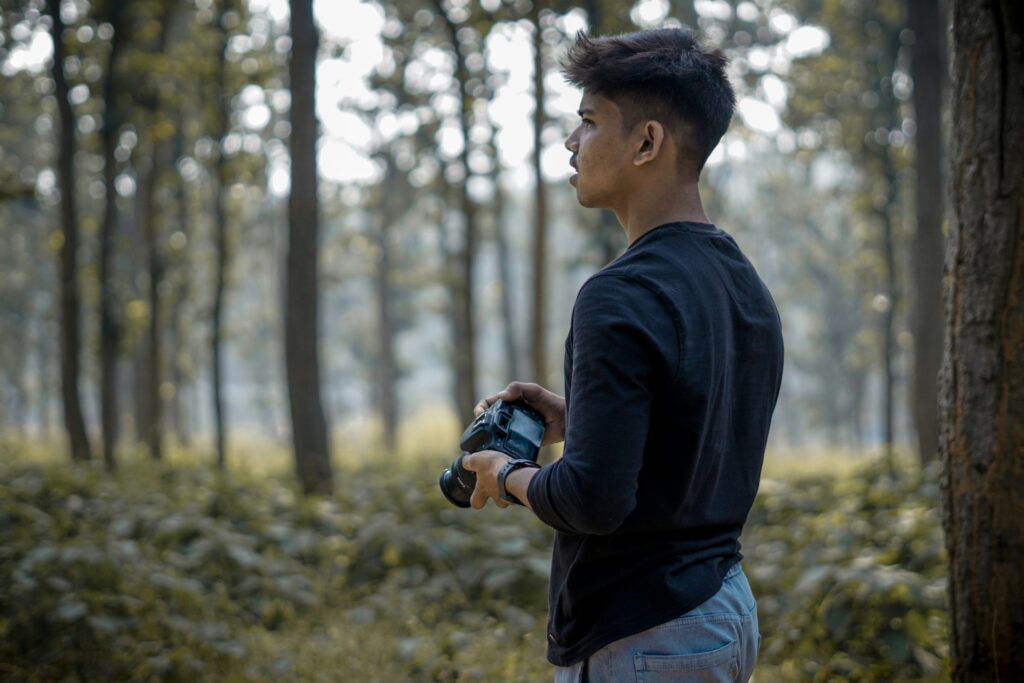 Man carrying a camera in a dense forest 