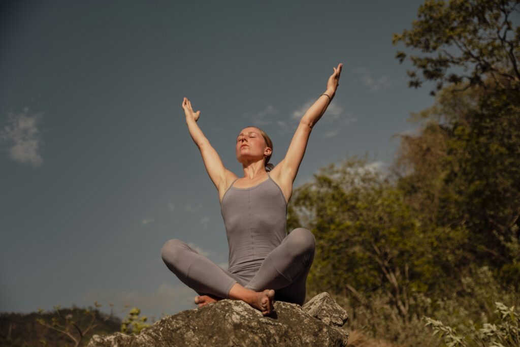 A woman sat on a rock while being in a Yoga position
