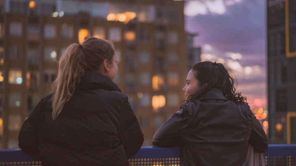 Two woman talking at a evening rooftop view 