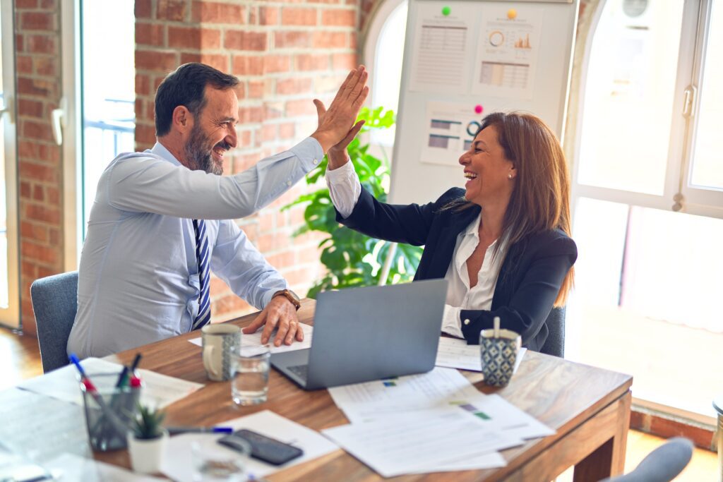 A man and a woman high-fiving each other in office.