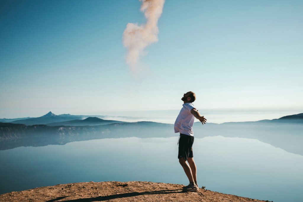 A man happily spreading his arms on top of a mountain