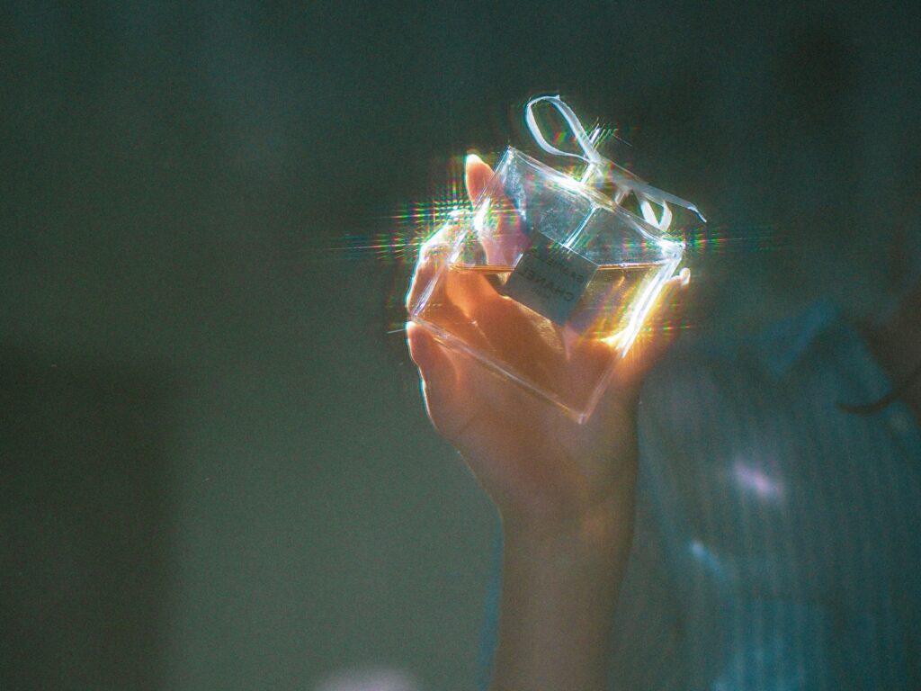 a blurry image of a hand holding up a perfume bottle