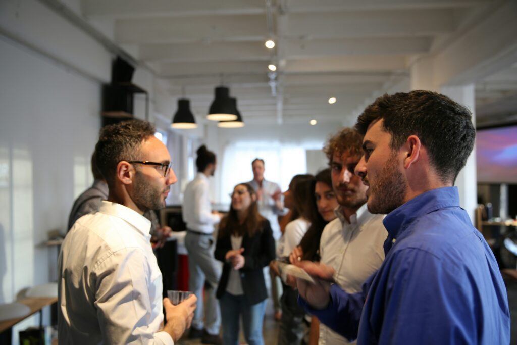 A group of young people speaking in business ware speaking with another person holding a drink.