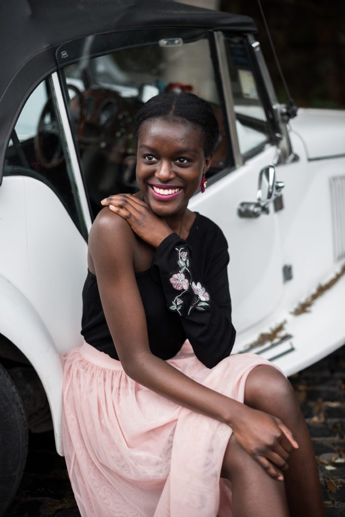 Former IGNITE Promotions Lead, Maya Marcus smiling in front of a car.
