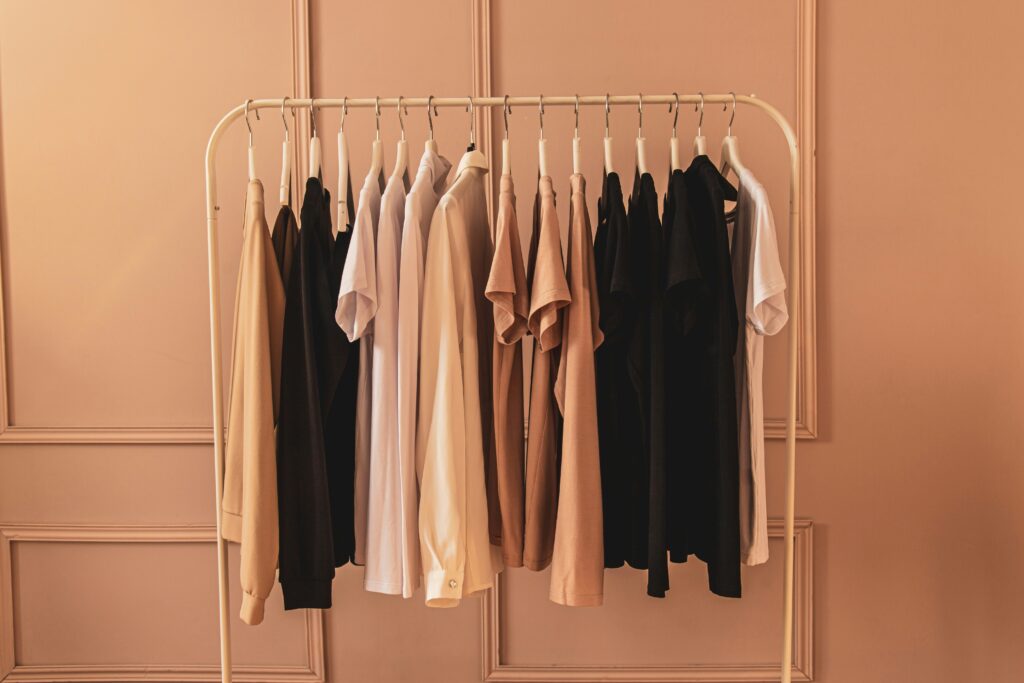 A clothing rack on a beige background with different shirts.