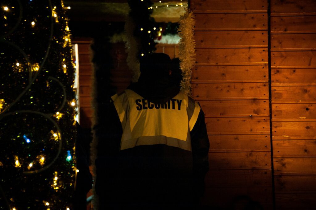 Photo of a dimly lit room with a man wearing a security vest