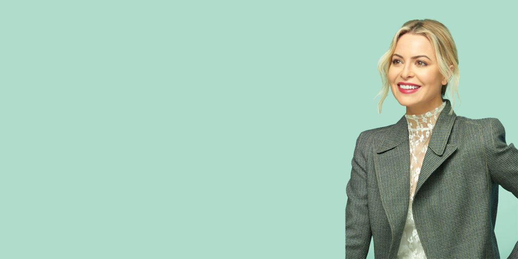 Sophia Amoruso smiling facing the left against a green background.