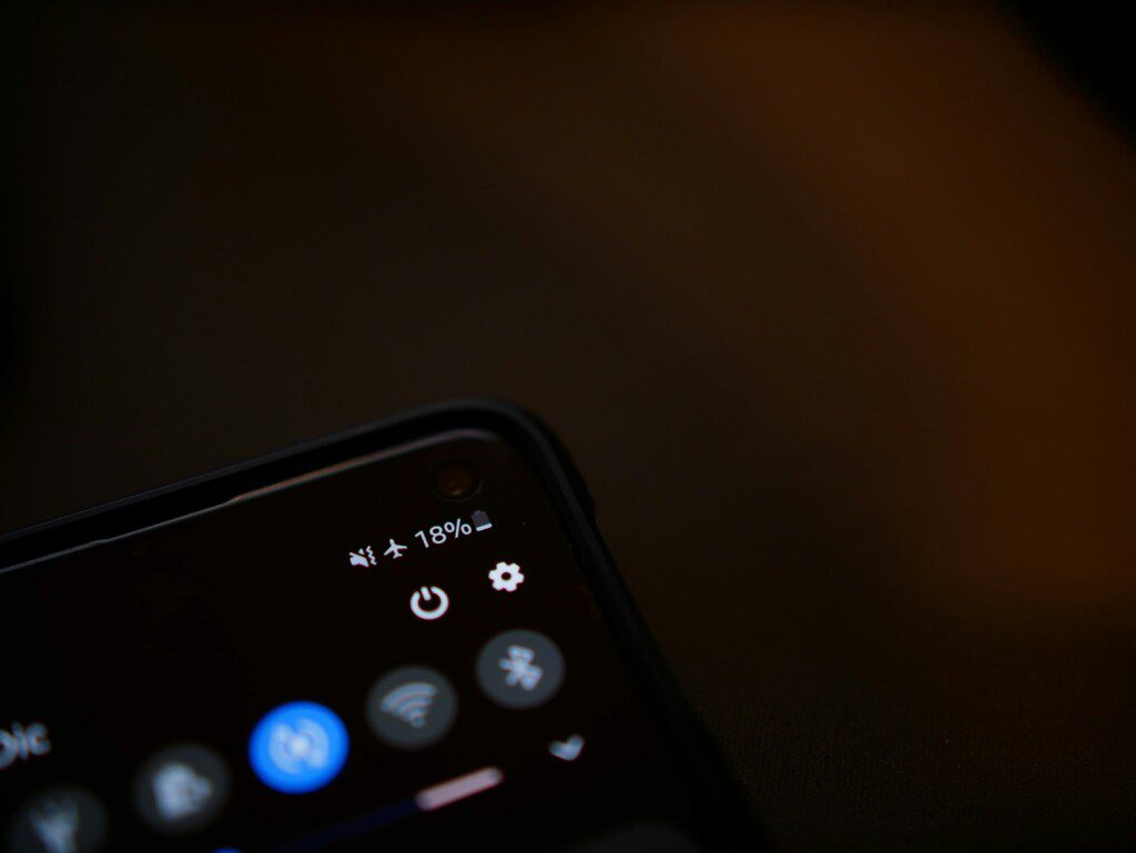 Close-up of a smartphone screen in dim lighting showing app icons and a battery indicator at 18%.