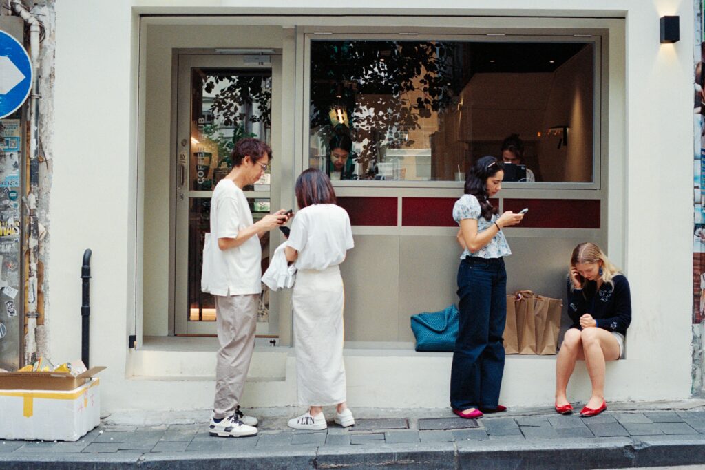 People sat outside a store and using their phone