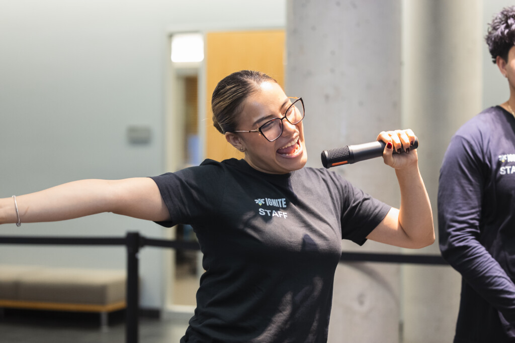 A student singing with a microphone in hand at the IGNITE Block Party.