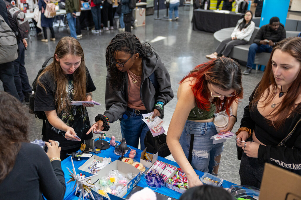 A group of students around at table at the IGNITE club's fair, talking with one another. 