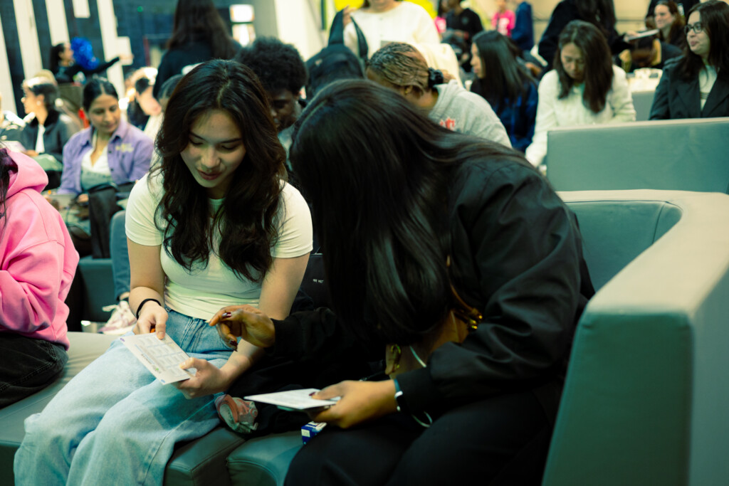 Two students sitting next to each other and socializing in the Student Centre at the North Campus.