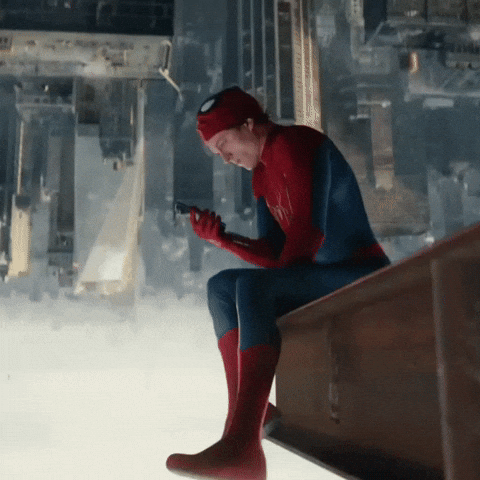 Spiderman sitting on the edge of a tall building and scrolling on his phone
