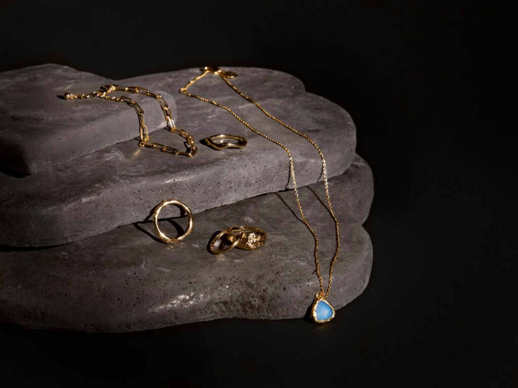  A rock with gold jewelry kept on top aesthetically