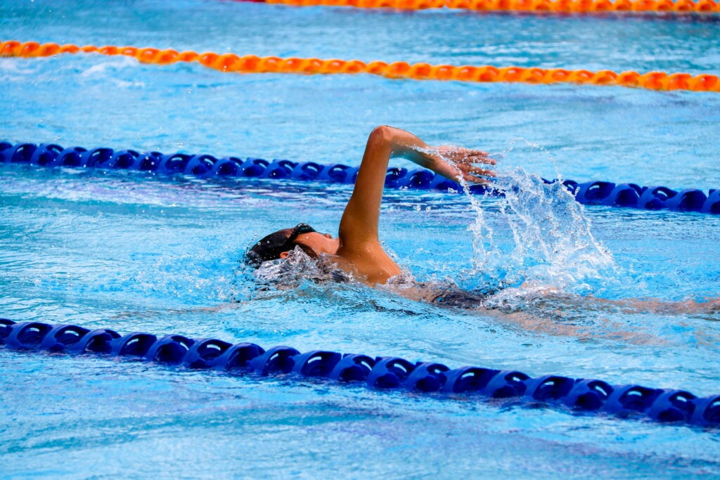 Man swimming front stroke in a lane pool.