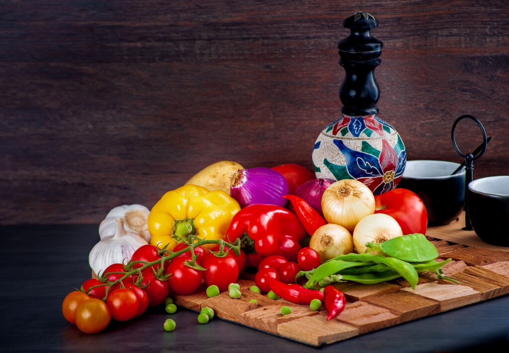 red, yellow, and green bell peppers on a brown wooden chopping board
