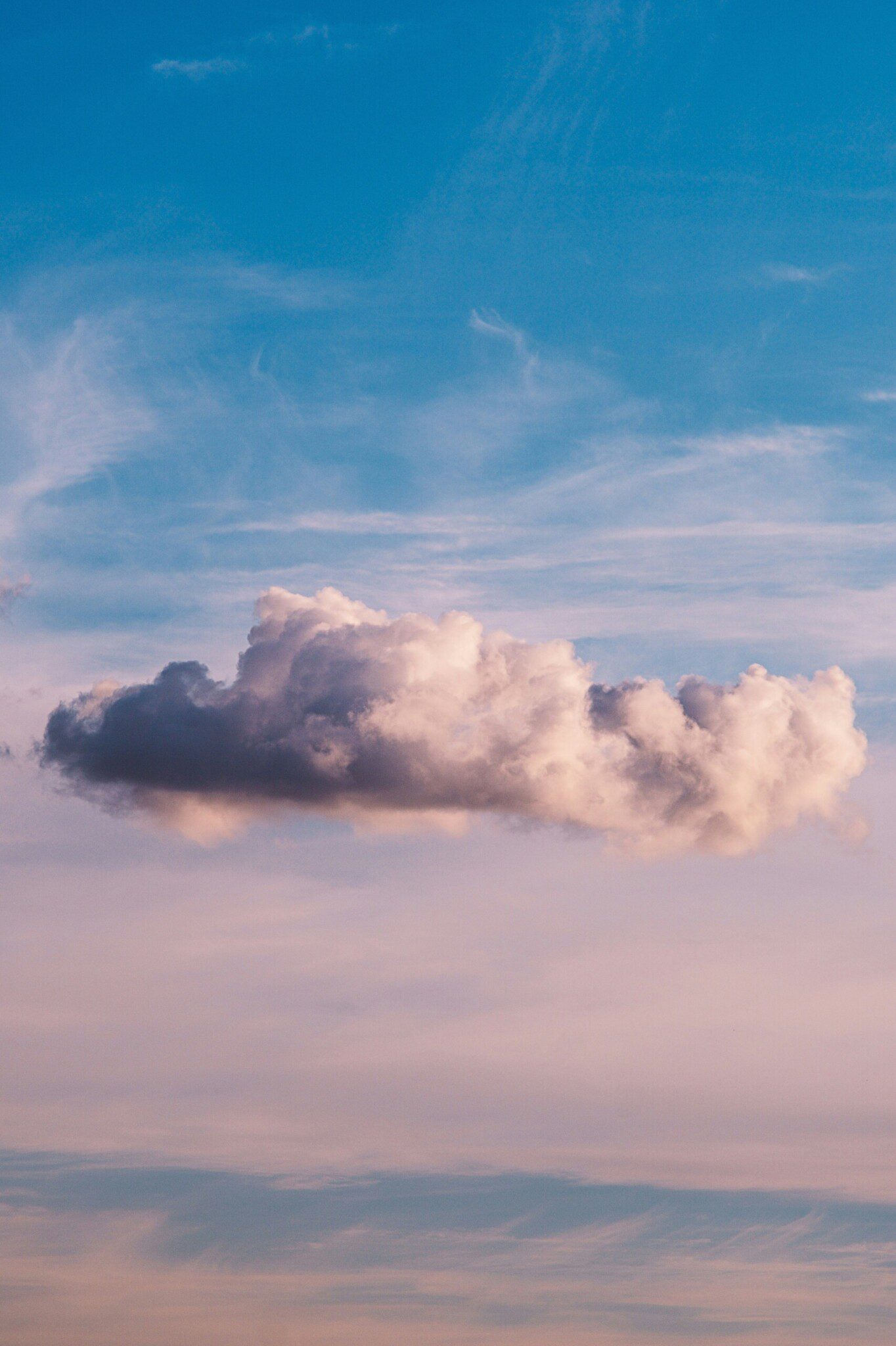 Large cloud floating alone in a blue, purple, and pink, sunset sky.